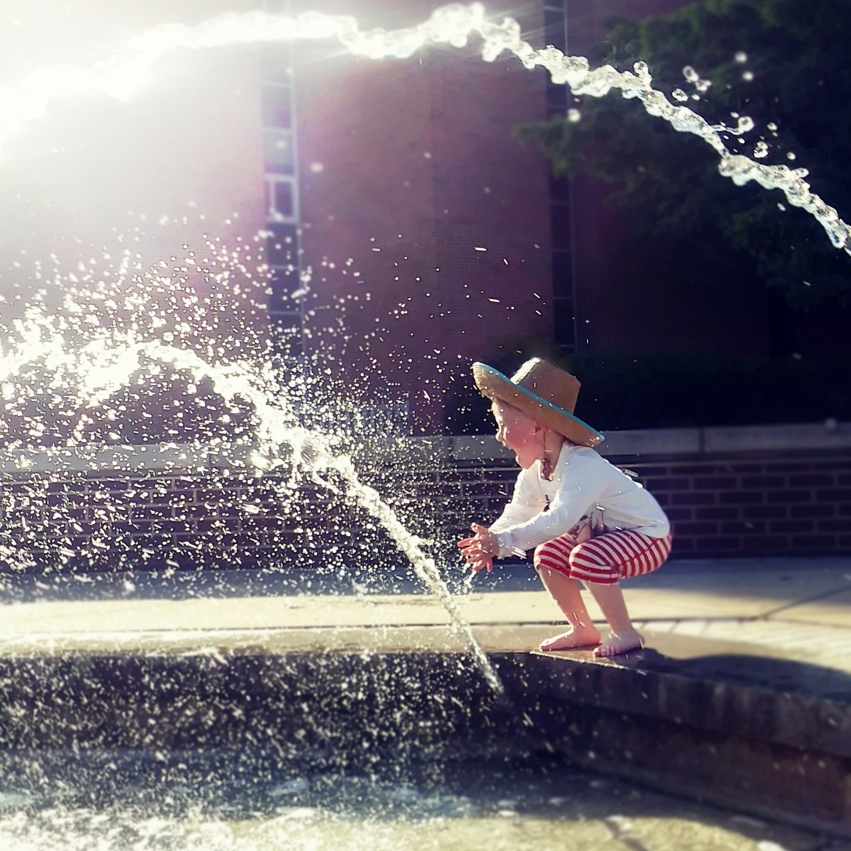 a young boy plays in a fountain at MSU