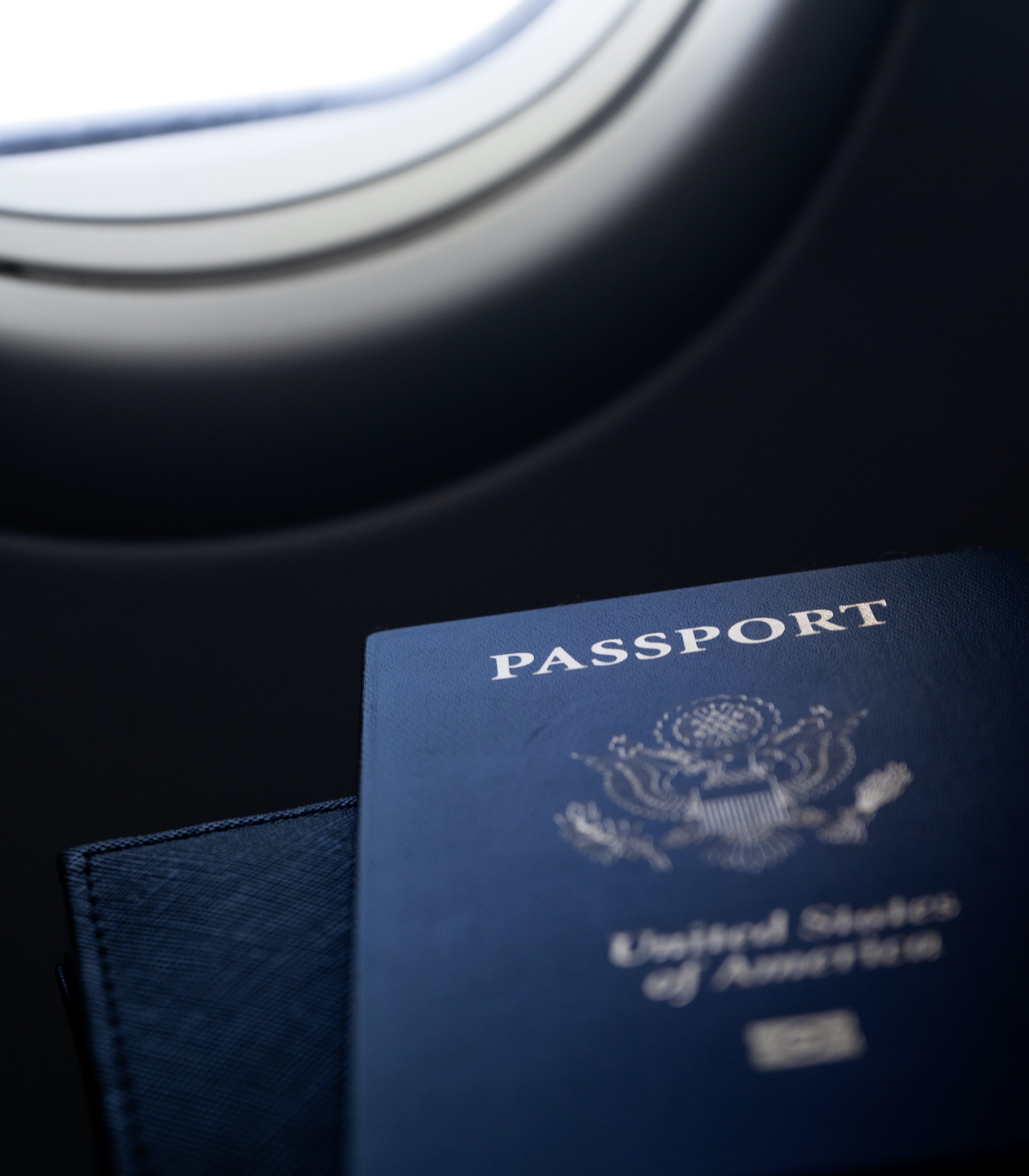 a passport sits next to an airplane window
