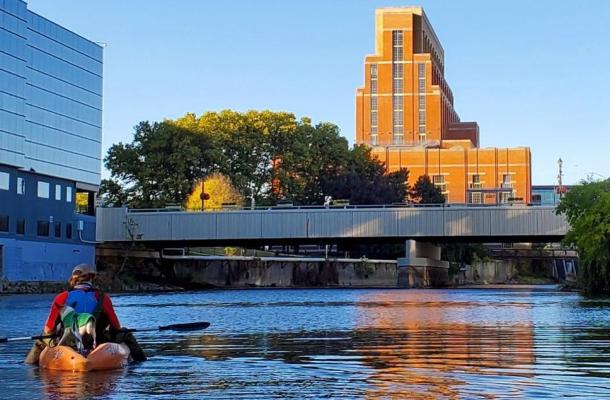 A man and his dog kayak on the river in Lansing