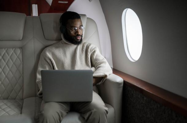 a man on an airplane with his laptop open in front of him