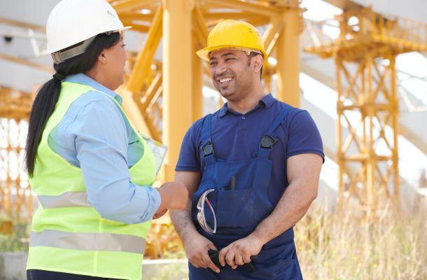 A Man with Yellow Hardhat Smiling at a Woman with Ppe